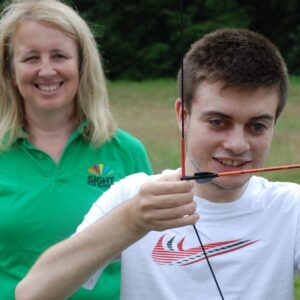 Volunteer Liz with Lee Roake who Sight for Surrey has supported since he was three years old, trying his hand at archery.