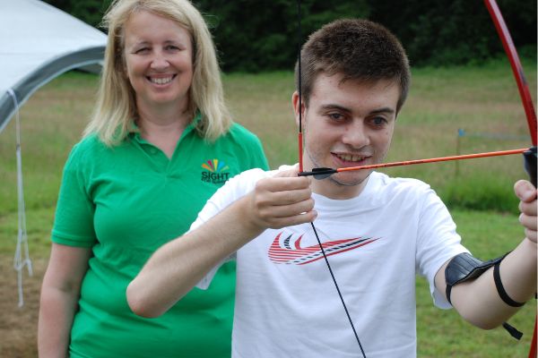 Volunteer Liz with Lee Roake who Sight for Surrey has supported since he was three years old, trying his hand at archery.
