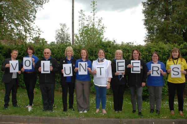 A line up of volunteers each holding a letter spelling out the word volunteers