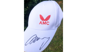 A white baseball cap with the emblem AMC and signed Andy on the peak of the cap.