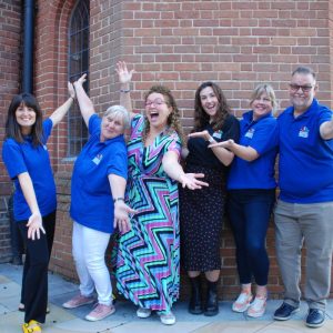 Image shows Yvonne Cobb with the Deaf Services Team from the charity they are standing in a line with their arms and hands outstretched.
