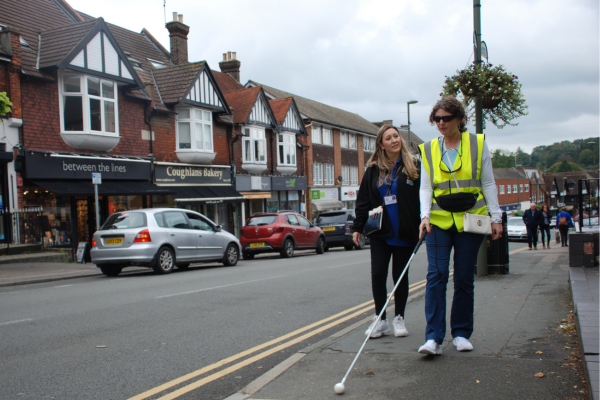 Image shows a lady being given long cane mobility training by a member of staff from the charity.