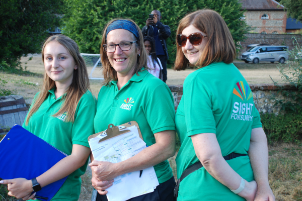 Image shows 3 women from the charity all wearing branded t-shirts, one is carrying a clipboard and they are all standing outside.