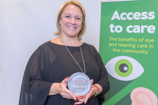 Image shows Diane Smith, Head of Adult Services holding the Community Impact Award, she is beaming at the camera.