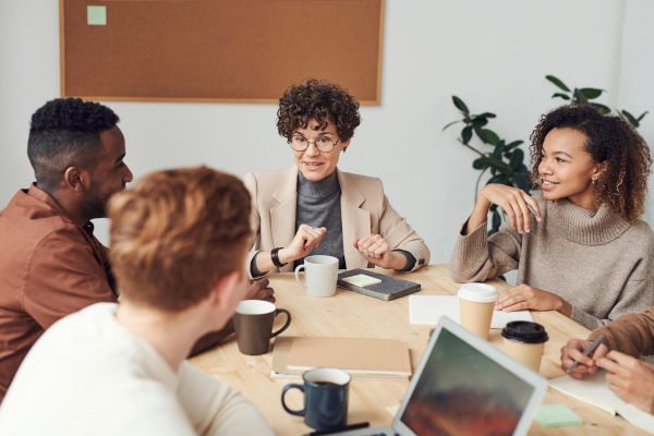 Image shows a group of people working together sitting round a table.