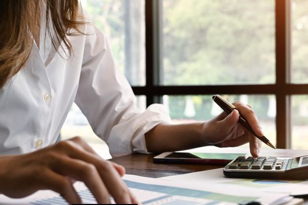 Image shows a lady holding a pen sitting at a desk.