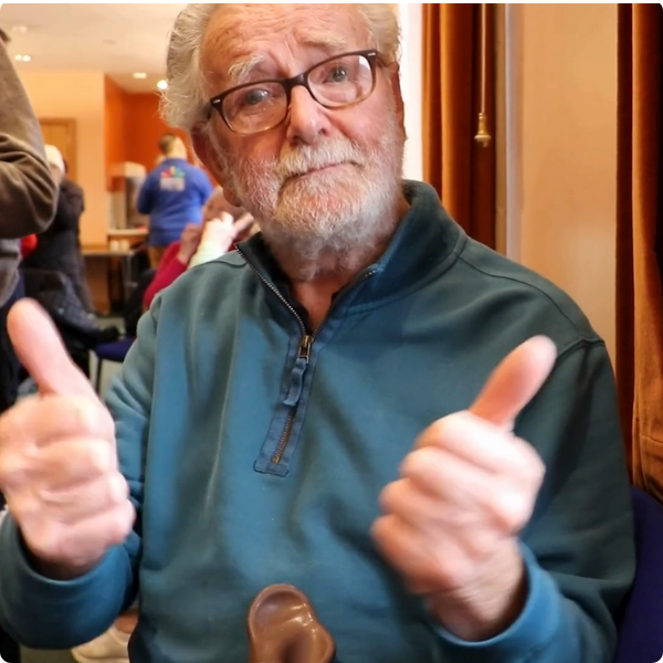A man is giving a thumbs up sign in British Sign Language