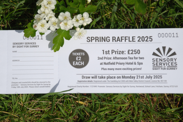Image of a Spring Raffle ticket book a sprig of white blossom is hugging the side of the book.
