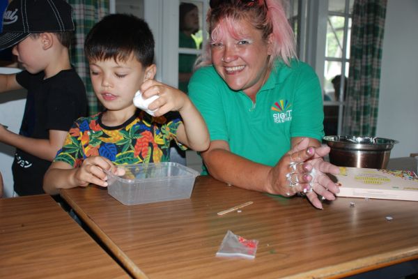 A CYPS Activity Worker is making slime at a table with a young boy the charity supports.