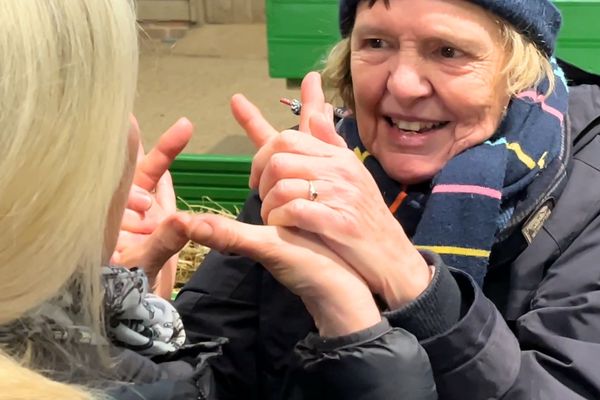 A lady is using Deafblind Manual communication.