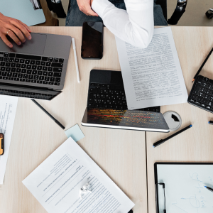 A desk with a laptop, note pad, pens and pencils.