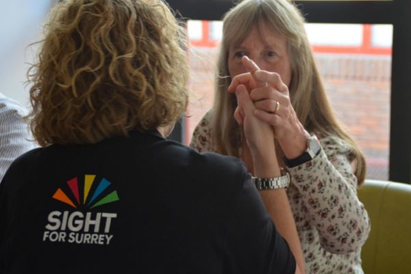 A member of staff from the charity is performing hands on signing with a deafblind lady we support.