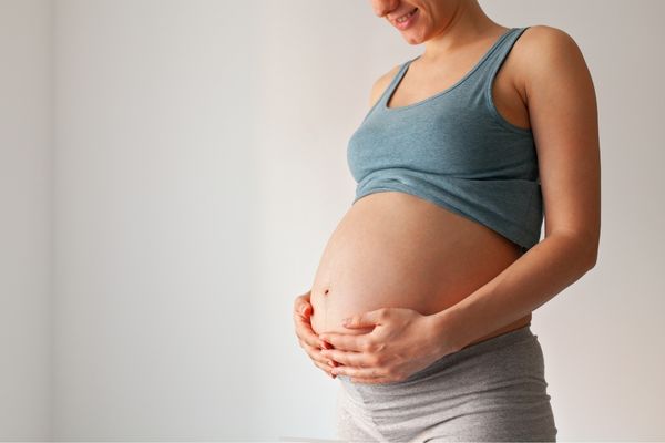 A pregnant woman with her hands around her belly