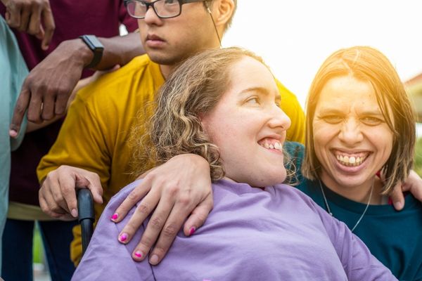 Two disabled women are next to each other and a disabled man is standing behind them.