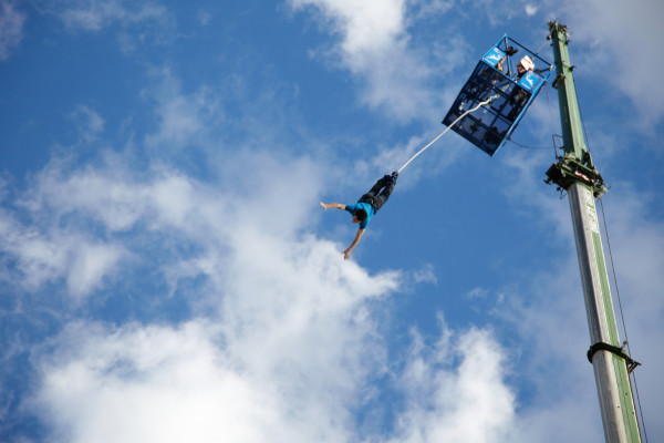 A person is diving down from a platform doing a bungee jump.