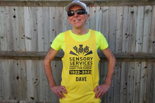 A man is wearing a branded charity t-shirt and he is wearing a cap and glasses.