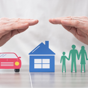 Cut-outs of a house, car and people are being protected by a pair of hands hovering over them.