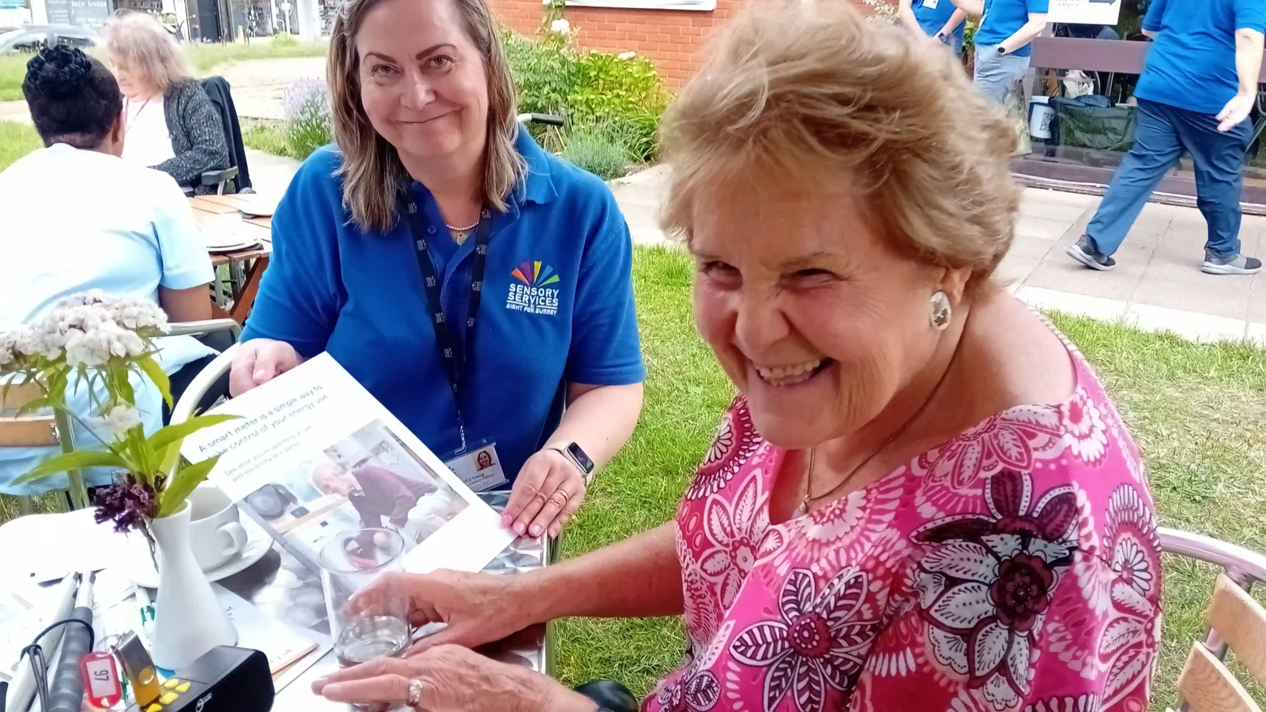 A lady looking though some equipment brochures with a member of staff from the charity.