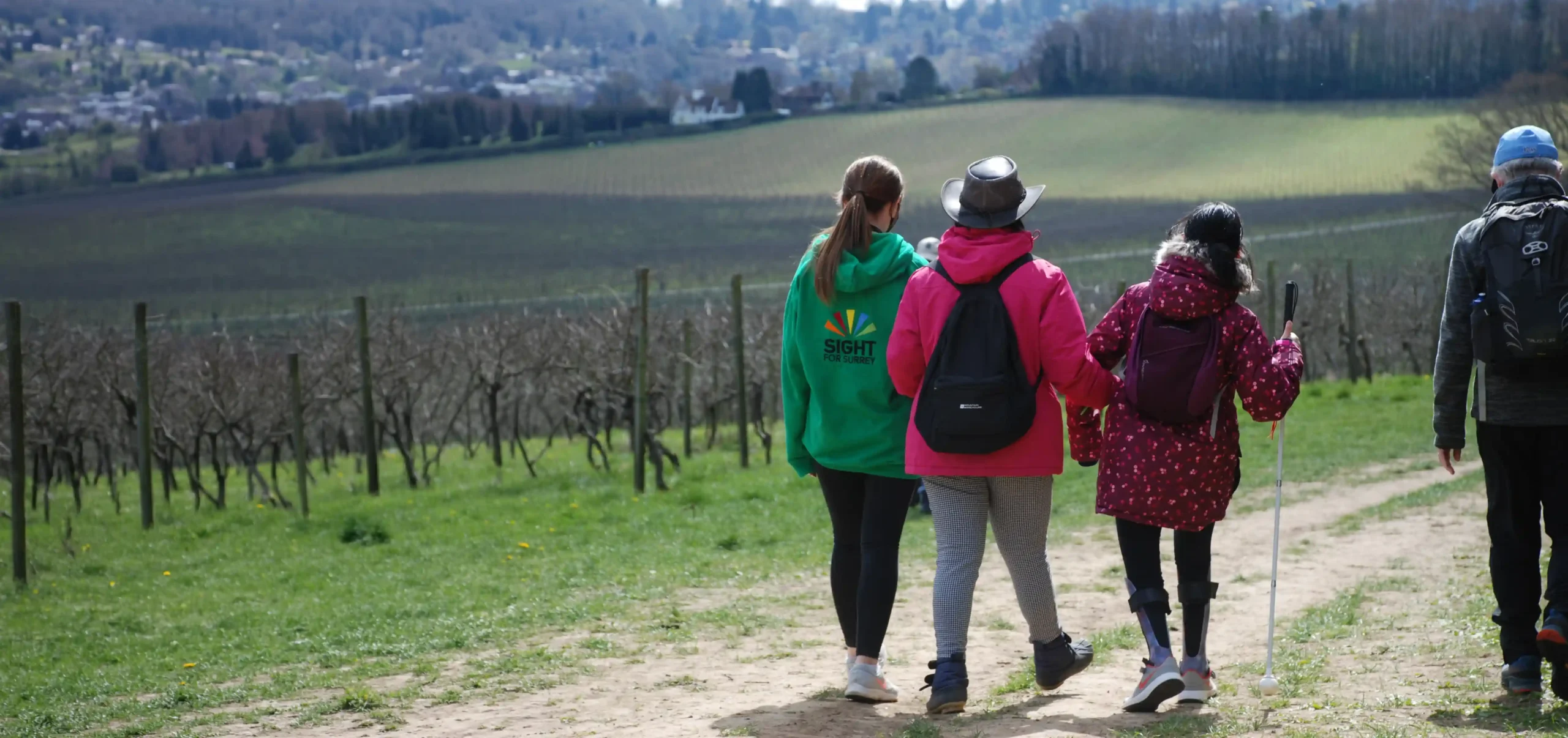 A member of staff walking outside with two VI young people.