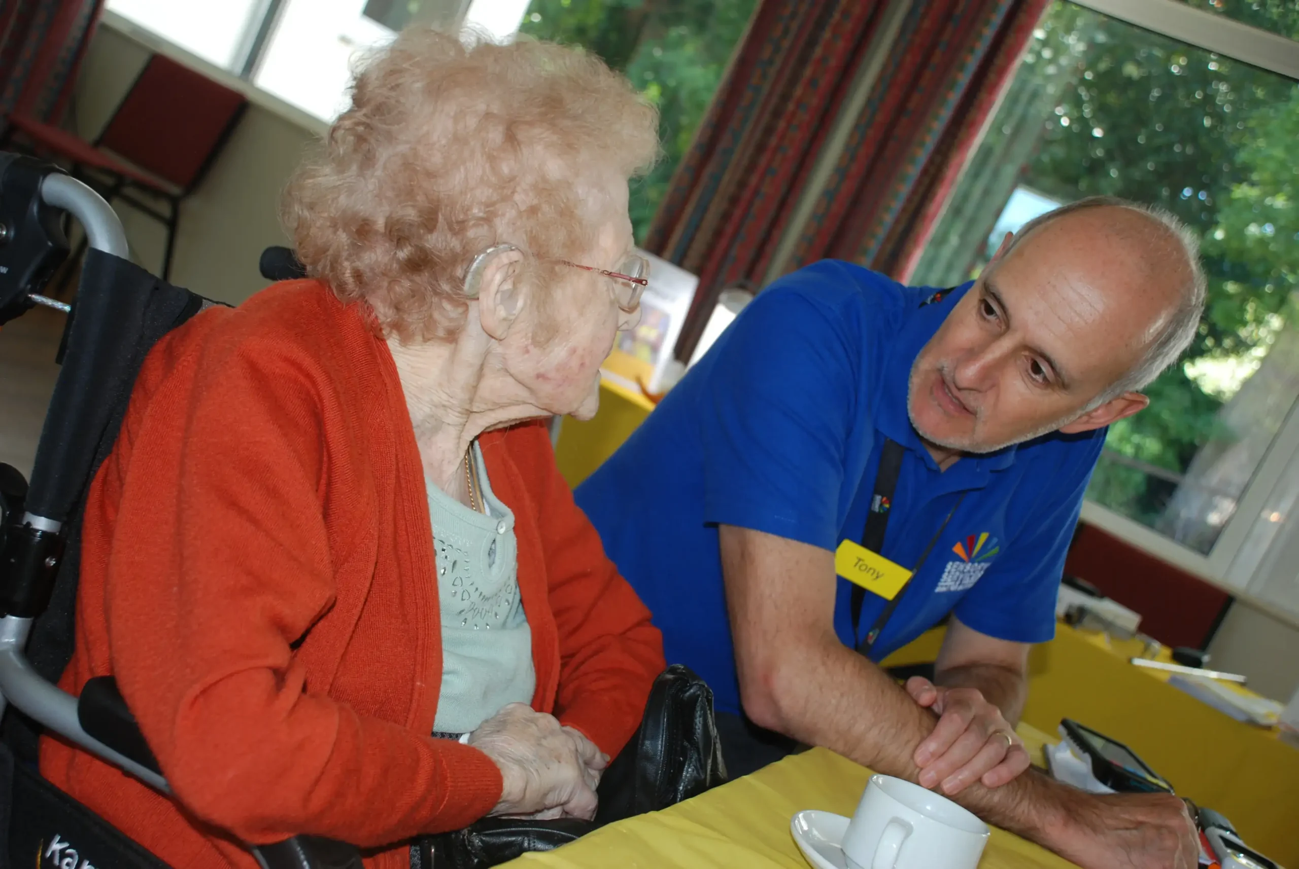 A man from the charity talking to a lady about sight and hearing loss equipment