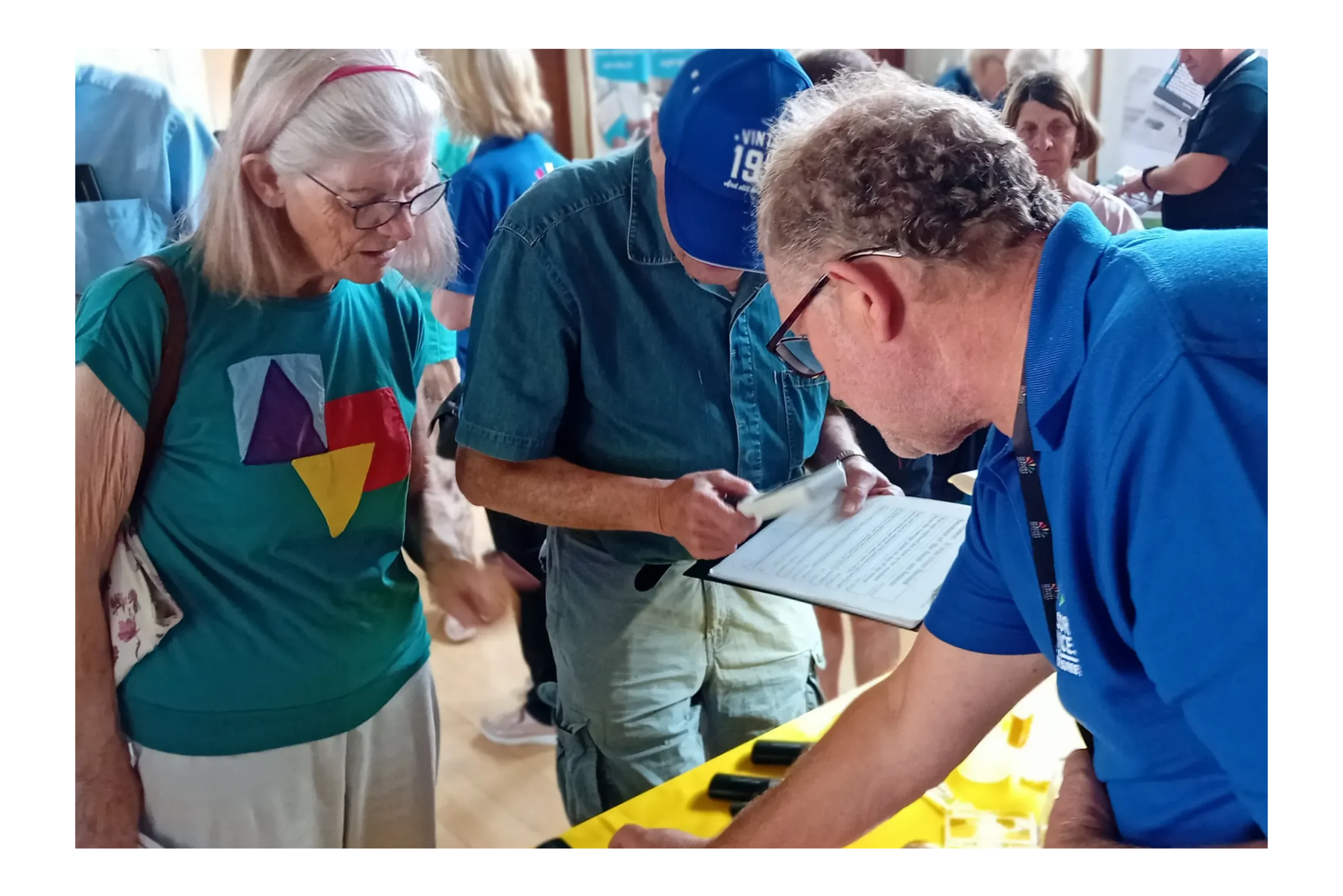 People at an event looking at sight and hearing loss equipment.