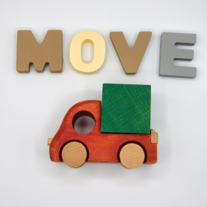 The words MOVE in block letters are above a wooden car with a large box in the back/boot.