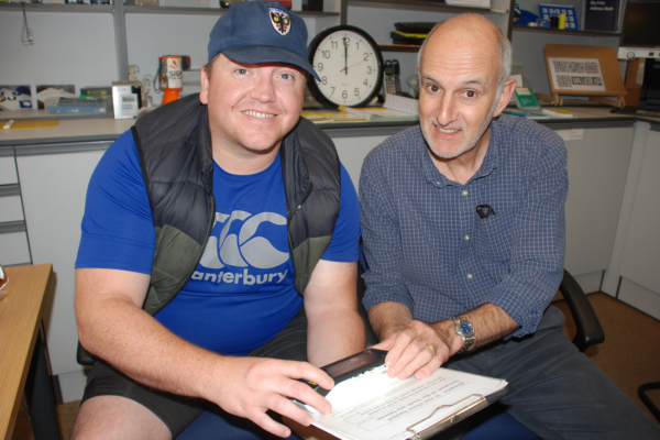 Resource Centre Manager, Tony, showing a visitor to the charity a selection of sight loss equipment