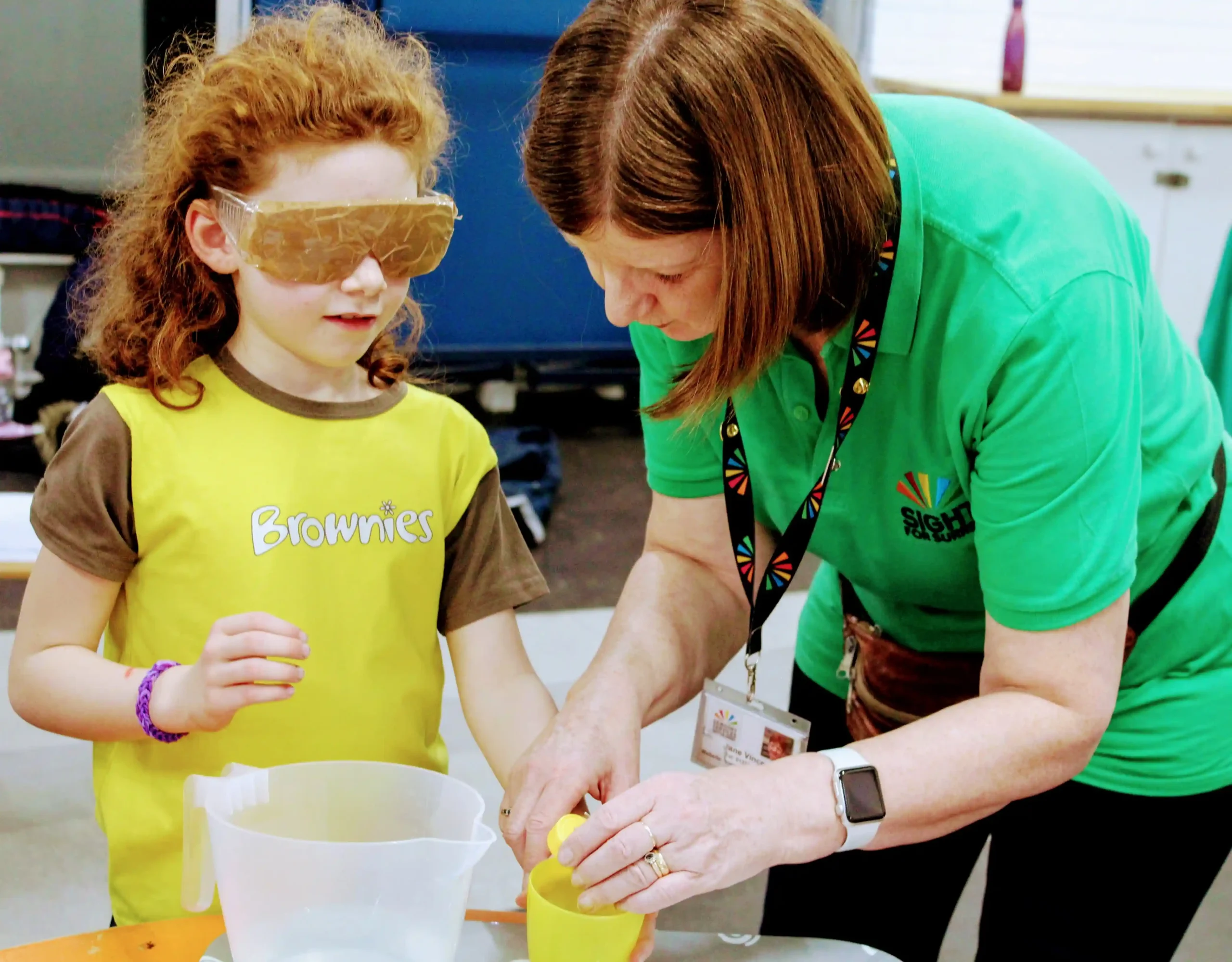 A member of the children and young people's team with a Brownie who is wearing a pair of sight loss simi specs.