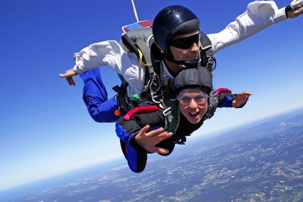 A person strapped to an instructor doing a sky dive.