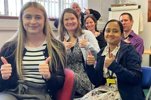 A group of staff from the charity are all giving the thumbs up 