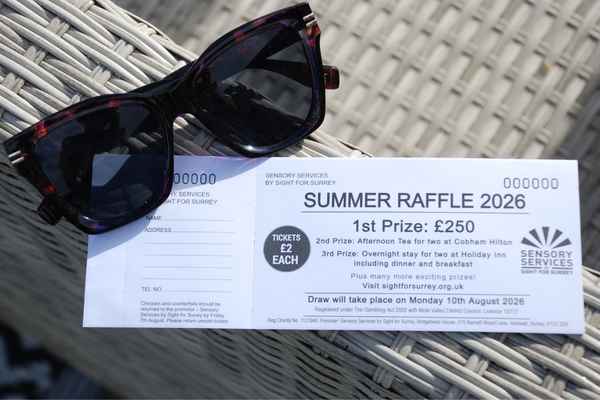 A raffle ticket book is lying on the edge of an outdoor dinning set propped with a pair of sunglasses.
