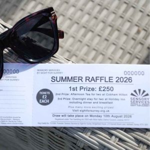 A raffle ticket book is lying on a summer outdoor sofa propped with a pair of sunglasses.