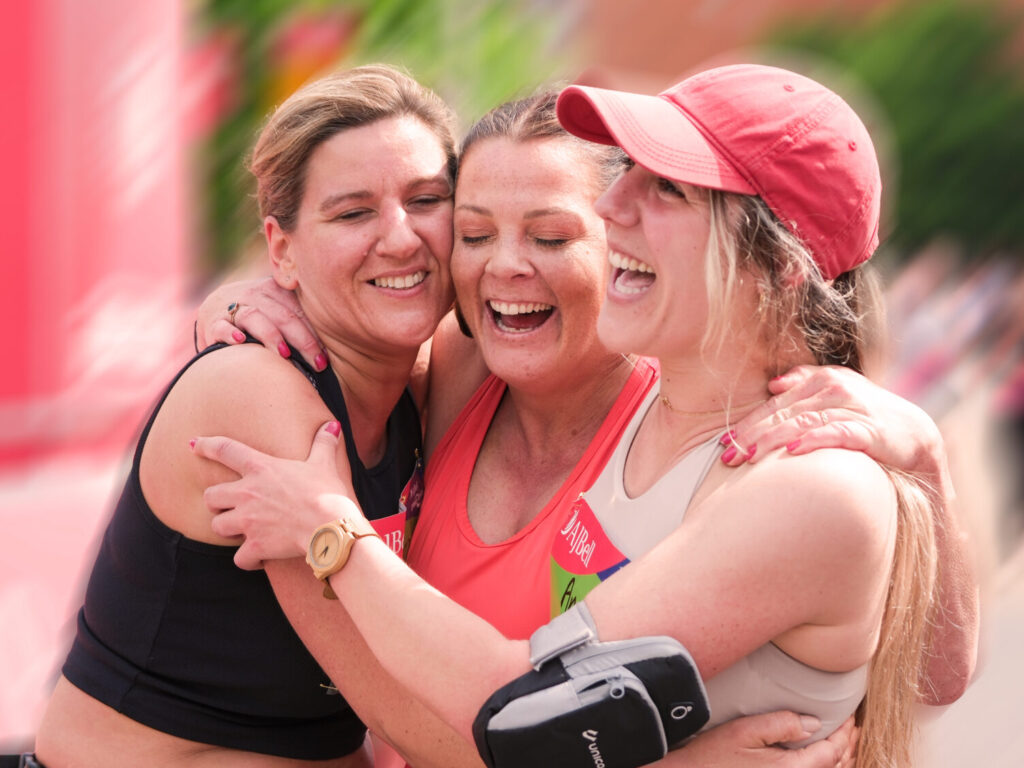 Three women hugging after finishing a race.