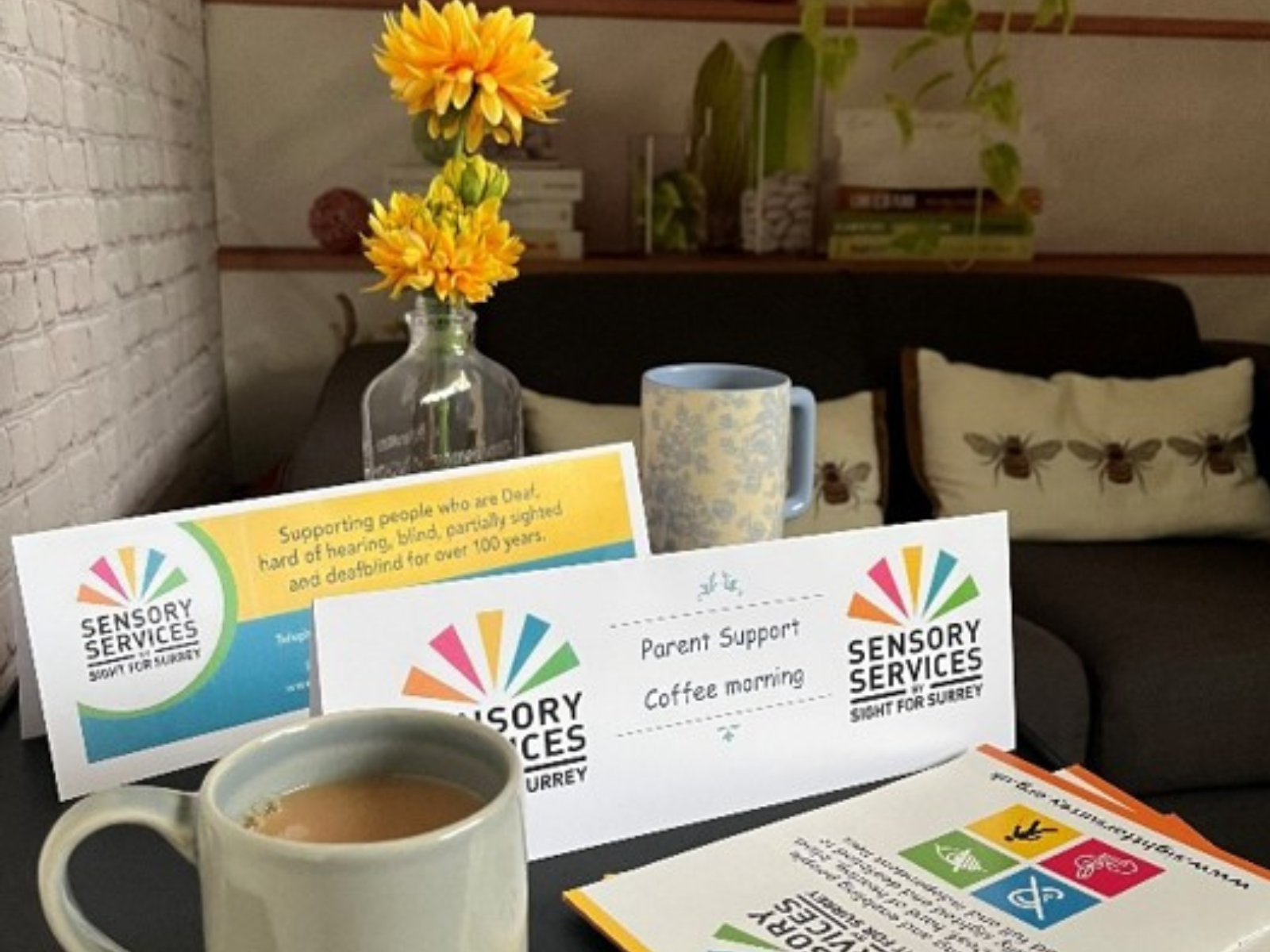 A table laden with a coffee mug, flowers and a sign saying Family Support Coffee Morning