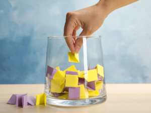 A large glass jar filled with raffle tickets with a hand pulling out a ticket