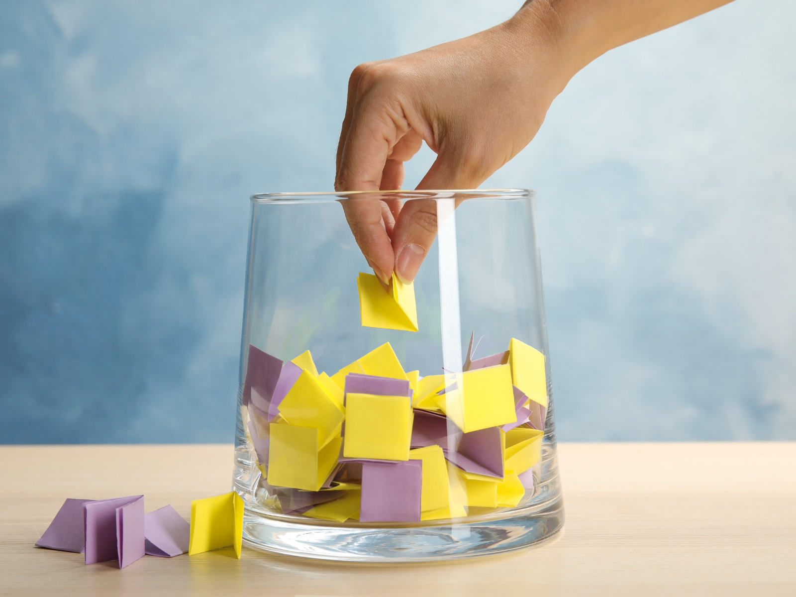 A large glass jar filled with raffle tickets with a hand pulling out a ticket